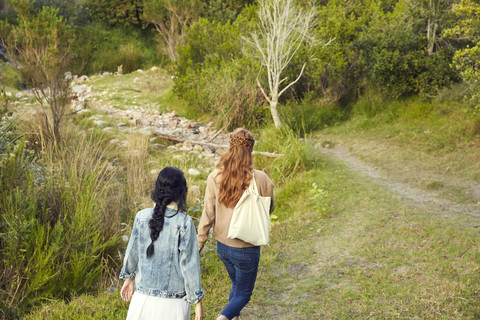 Rückenansicht von zwei jungen Frauen, die in der Natur spazieren gehen, lizenzfreies Stockfoto