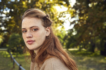 Porträt einer rothaarigen jungen Frau mit Sommersprossen in einem Park - SRYF00469