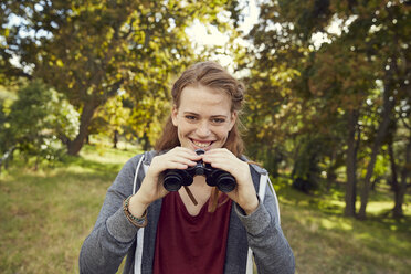 Portrait of smiling young woman using binoculars - SRYF00474