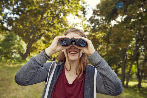 Smiling young woman using binoculars - SRYF00475