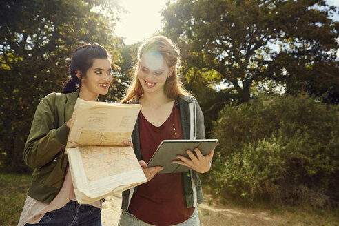 Zwei junge Frauen mit Tablet und Karte in der Natur - SRYF00480