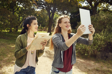 Zwei junge Frauen mit Tablet und Karte in der Natur - SRYF00481