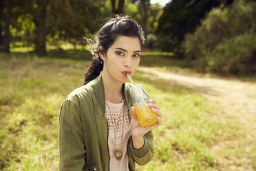 Portrait of young woman drinking juice in nature - SRYF00485