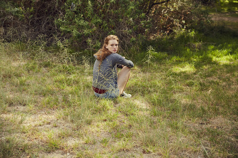 Porträt einer jungen Frau auf einer Wiese sitzend, lizenzfreies Stockfoto