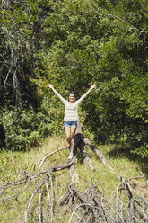 Lächelnde junge Frau balanciert auf einem Baumstamm - SRYF00510