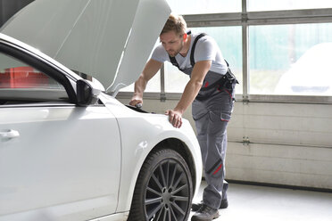 Automechaniker in einer Werkstatt bei der Arbeit am Auto - LYF00684