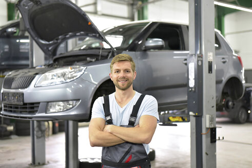 Porträt eines lächelnden Automechanikers in einer Werkstatt - LYF00699