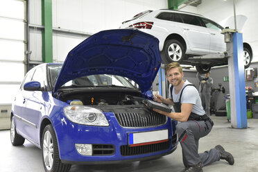 Car mechanic in a workshop using diagnostics computer at car - LYF00711