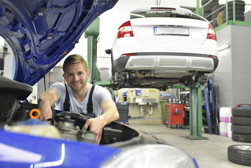 Automechaniker in einer Werkstatt, der ein Auto untersucht - LYF00713