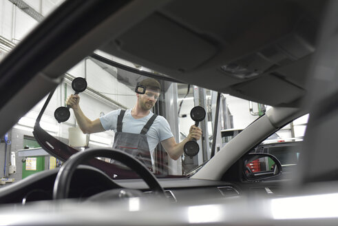 Car mechanic in a workshop changing car window - LYF00714