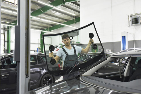 Automechaniker in einer Werkstatt wechselt Autofenster - LYF00716