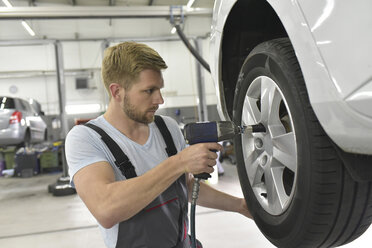 Automechaniker in einer Werkstatt wechselt Autoreifen - LYF00718