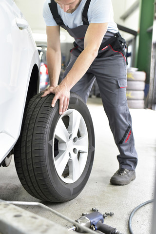Car mechanic in a workshop changing car tyre stock photo