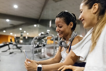 Zwei Frauen haben Spaß mit ihrem Smartphone nach dem Training im Fitnessstudio - MGOF03258