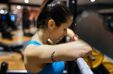 Erschöpfte junge Frau nach einem Workout im Fitnessstudio - MGOF03265