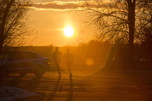 Silhouette von zwei Joggern im Winter bei Sonnenuntergang - KNTF00845