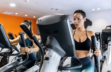 Zwei Frauen trainieren im Fitnessstudio auf einem Ellipsentrainer - MGOF03268