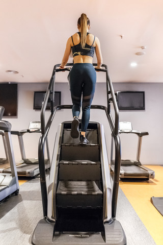 Junge Frau trainiert im Fitnessstudio mit einer Treppenmaschine, lizenzfreies Stockfoto