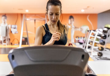 Young woman training in gym on a treadmil - MGOF03277