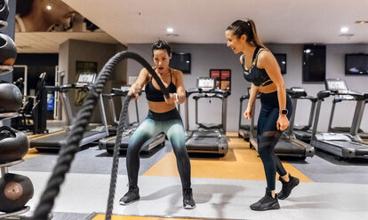 Woman doing battle rope exercise at gym - MGOF03284