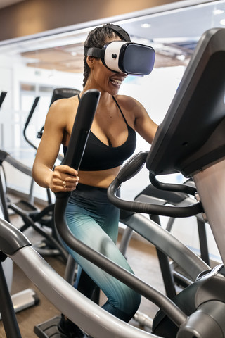 Woman wearing VR glasses on an elliptical traine in the gym stock photo