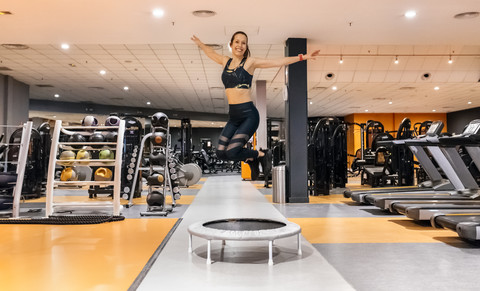 Junge Frau springt in der Turnhalle, lizenzfreies Stockfoto