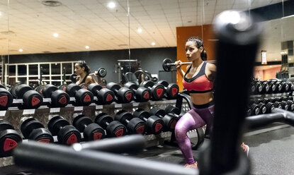 Woman lifting barbell in gym - MGOF03304