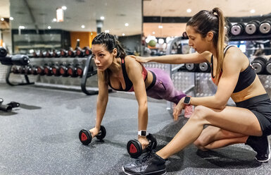 Frau mit ihrem Trainer beim Training im Fitnessstudio - MGOF03318