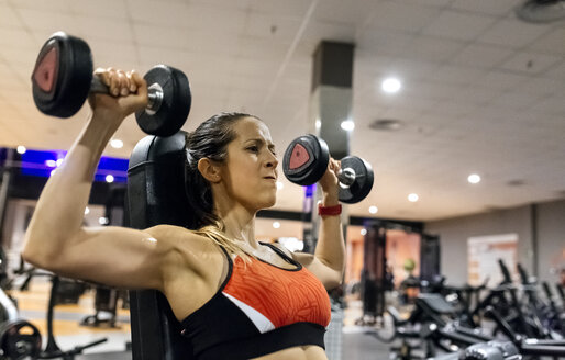 Frau hebt Hanteln im Fitnessstudio - MGOF03321