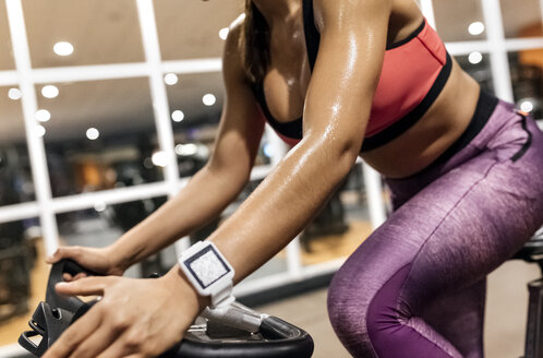 Nahaufnahme einer Frau auf einem Spinningrad im Fitnessstudio - MGOF03326