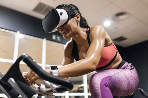 Woman with VR glasses on spinning bike in the gym stock photo