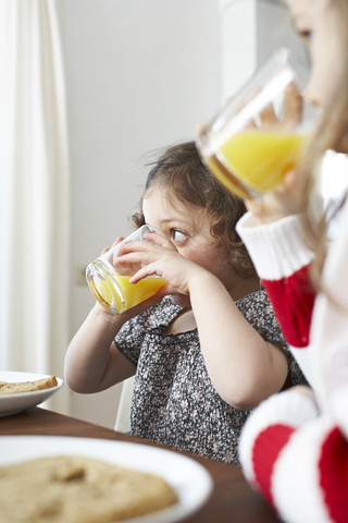 Kleine Mädchen trinken Orangensaft am Frühstückstisch, lizenzfreies Stockfoto