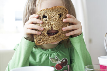 Kleines Mädchen schaut durch Löcher in einer Brotscheibe - FSF00839