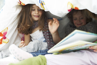 Three little children with book together under blanket - FSF00845