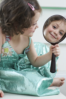 Spiegelbild eines lächelnden kleinen Mädchens vor einem Handspiegel - FSF00849