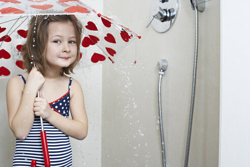 Porträt eines lächelnden kleinen Mädchens unter der Dusche mit Regenschirm - FSF00851