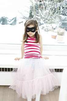 Porträt eines kleinen Mädchens mit Maske auf dem Fensterbrett sitzend - FSF00857