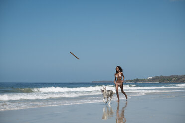 Mexiko, Riviera Nayarit Strand, junge Frau läuft mit Husky-Hund - ABAF02151