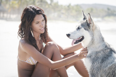 Mexiko, Riviera Nayarit Strand, junge Frau sitzt mit Husky-Hund - ABAF02153