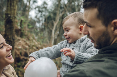 Glückliche Familie spielt mit einem Luftballon im Wald - DAPF00726