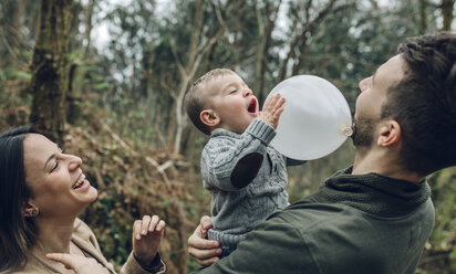 Glückliche Familie spielt mit einem Luftballon im Wald - DAPF00727