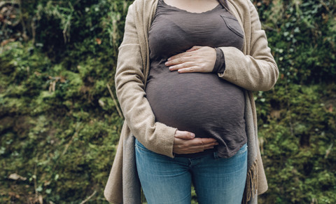 Nahaufnahme einer schwangeren Frau in der Natur, lizenzfreies Stockfoto