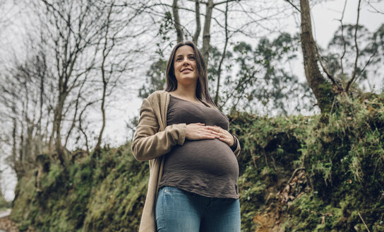 Lächelnde schwangere Frau im Wald im Herbst - DAPF00733