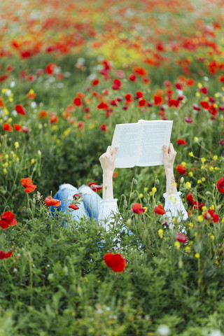 Woman lying in a field reading a book stock photo