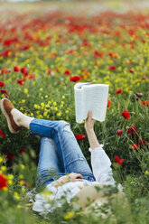 Frau liegt auf einem Feld und liest ein Buch - JPF00190