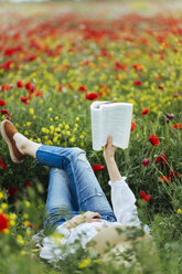 Woman lying in a field reading a book - JPF00190