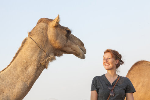 VAE, glückliche Frau mit Blick auf ein Kamel - MMAF00086