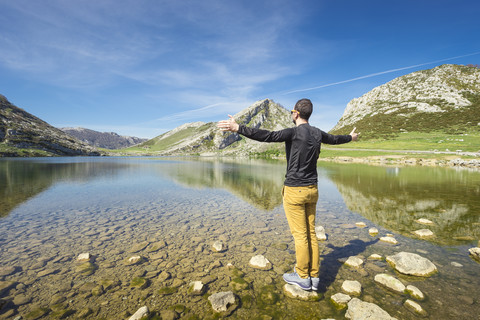 Spain, Asturias, Picos de Europa National Park, man standing with raised arms at Lakes of Covadonga stock photo