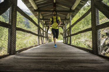 Italy, Alagna, man running on wooden bridge in the mountains - ZOCF00268