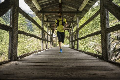 Italien, Alagna, Mann läuft auf Holzbrücke in den Bergen - ZOCF00268